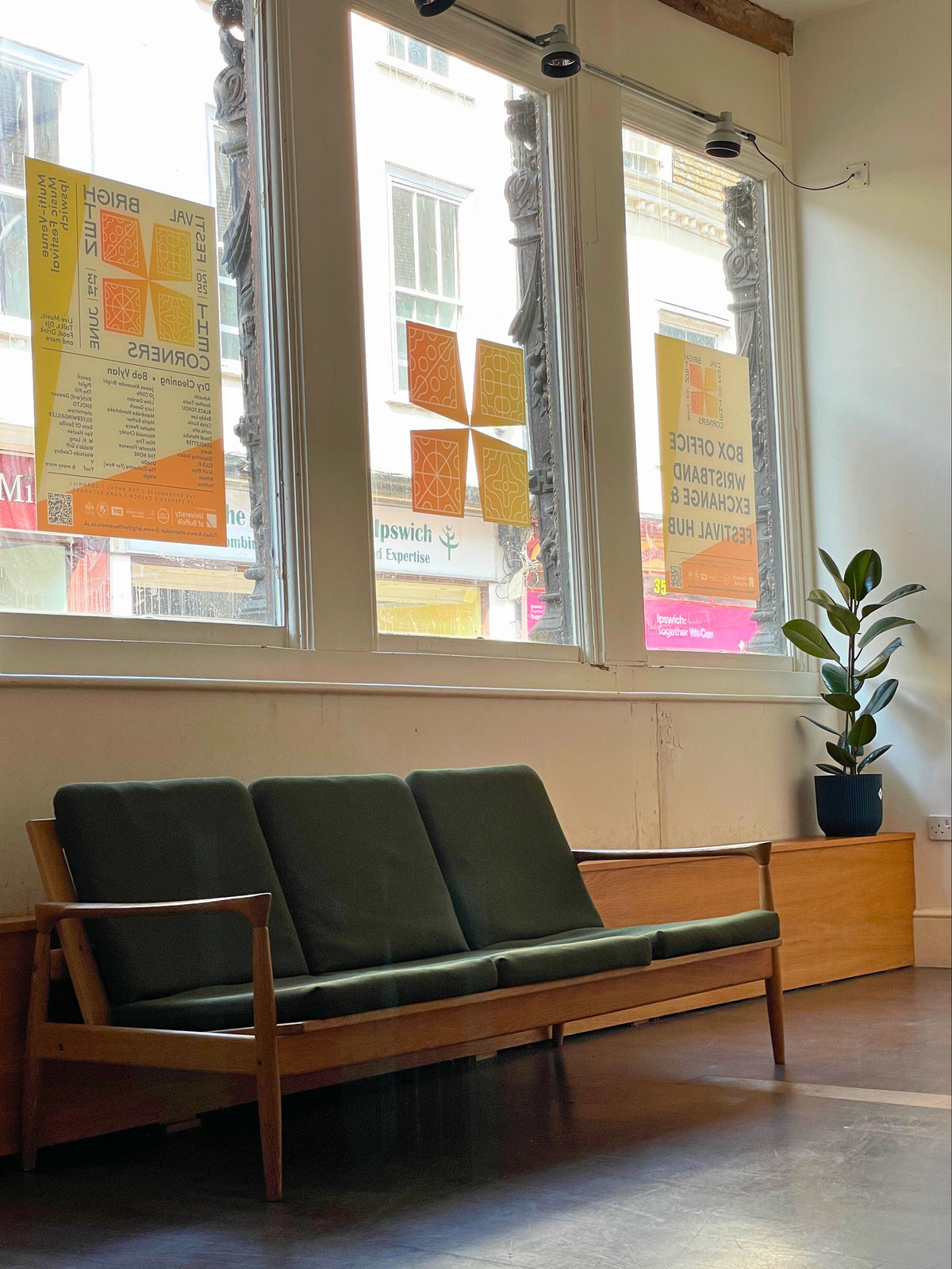 Green sofa in a room with large windows and posters on the wall