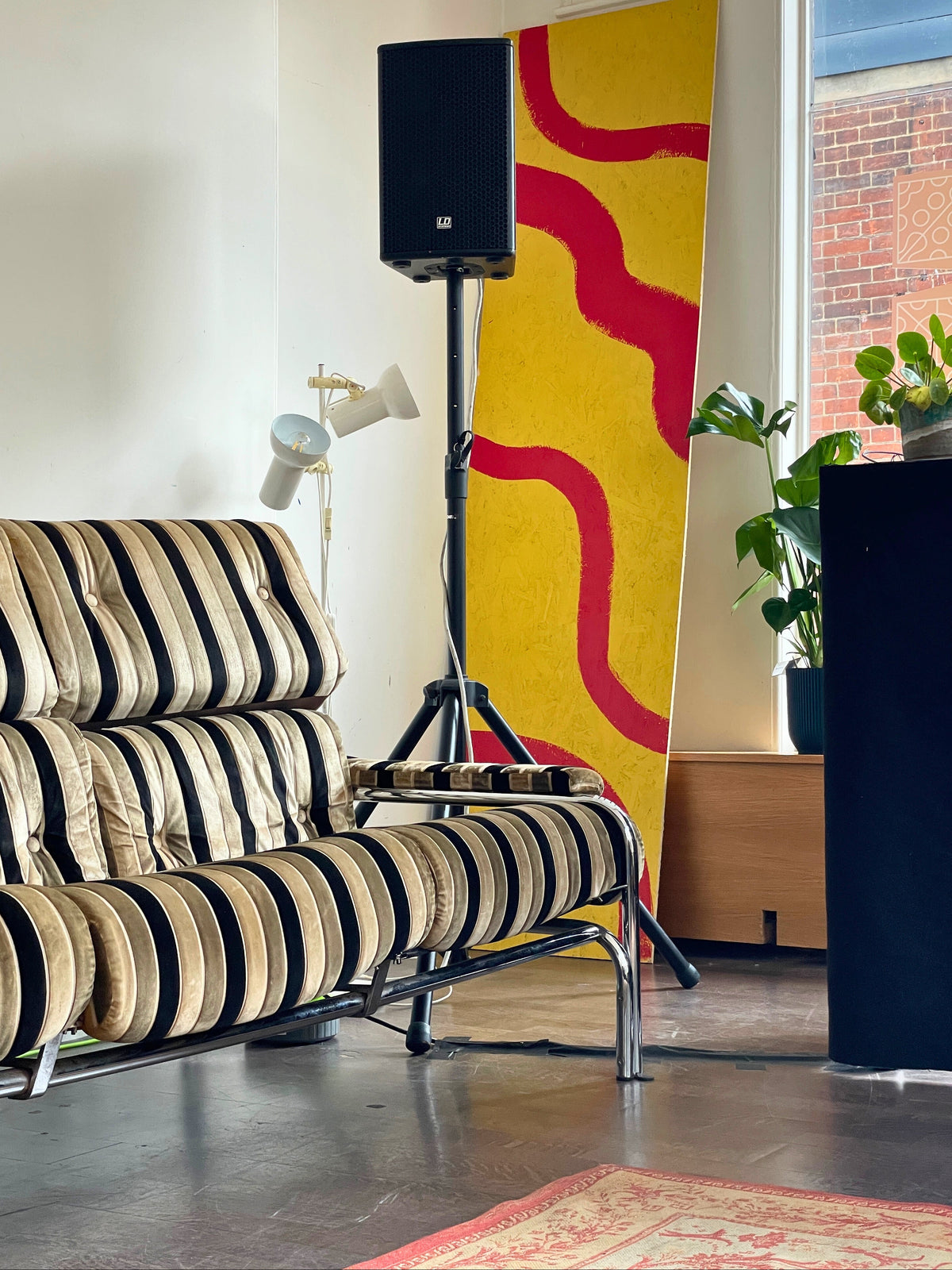 Modern living room set up with striped sofa, colourful abstract art and decorative elements.