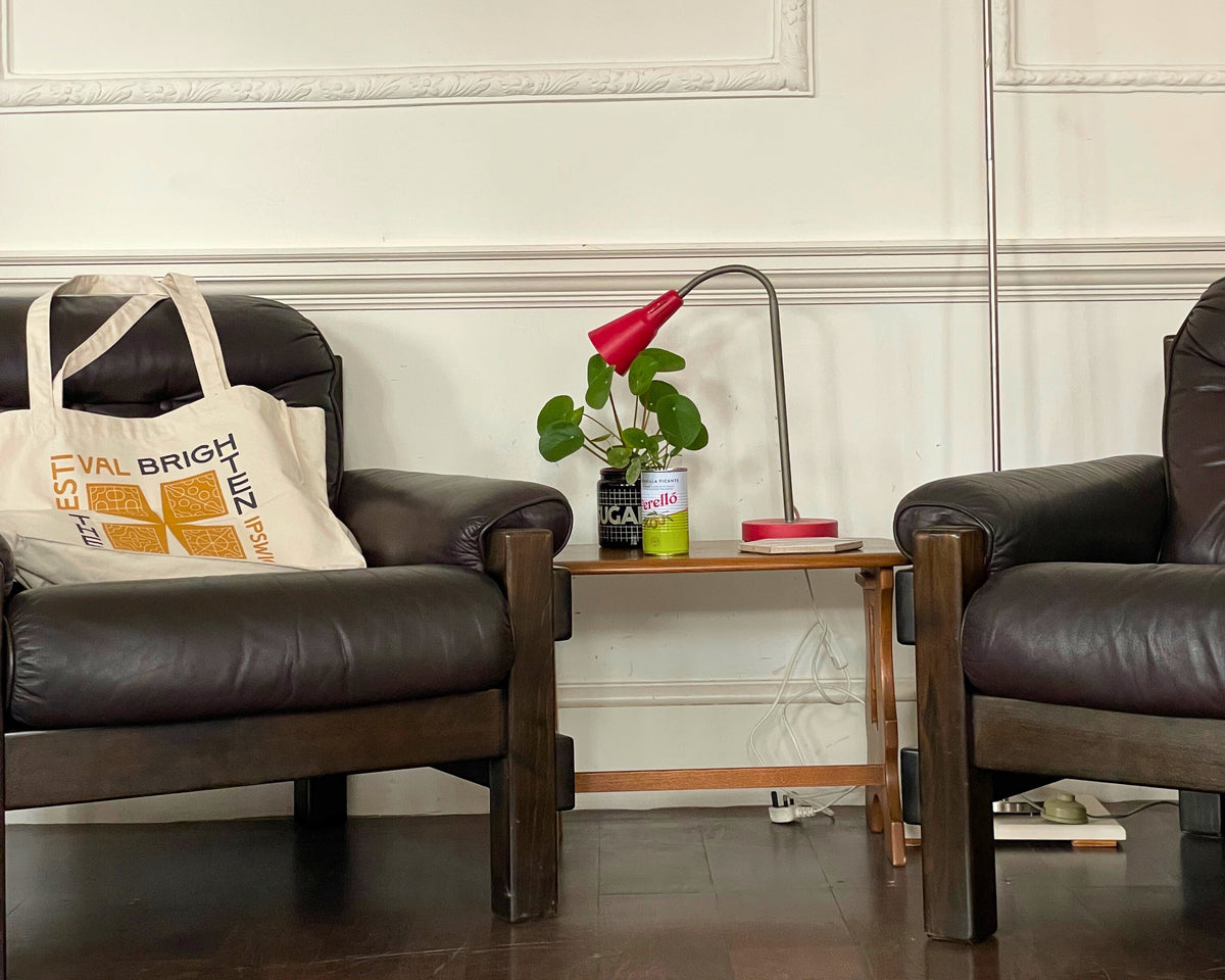 Two dark leather chairs in a room with a small table and decorative items.